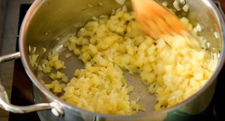 Zwiebeln und Kartoffeln in Butter in einer Pfanne mit dickem Boden dünsten.