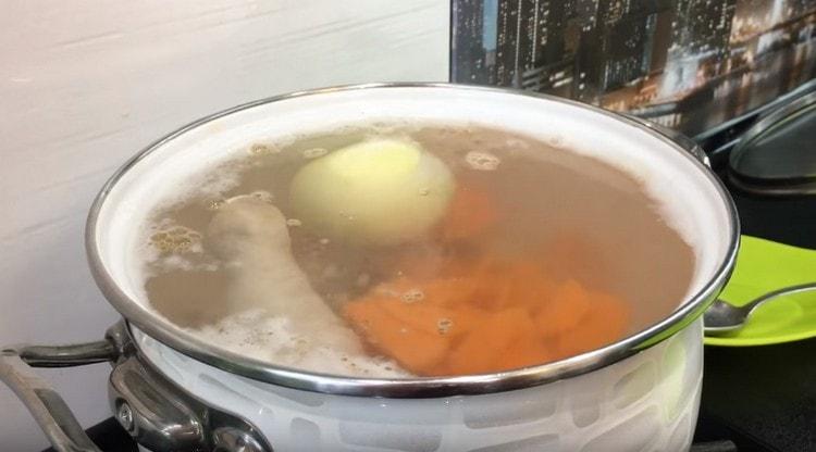Σε ένα ζεστό ζωμό, απλώστε τα καρότα, καθώς και ένα αποφλοιωμένο ολόκληρο κρεμμύδι.