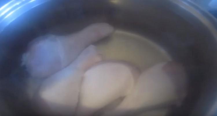 Wir verteilen die Hähnchenkeulen in einer Pfanne, bringen sie zum Kochen und lassen das Wasser abtropfen.