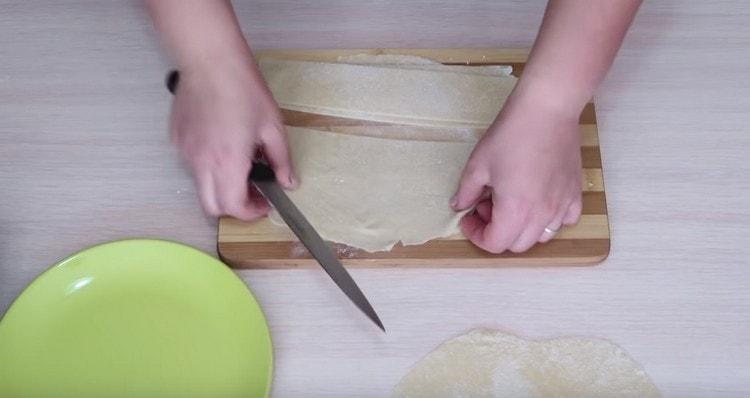 Κόψτε την τυλιγμένη ζύμη σε λωρίδες πλάτους 5 cm.