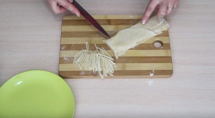 Piega le strisce di pasta una sopra l'altra e tagliatele a tagliatelle.