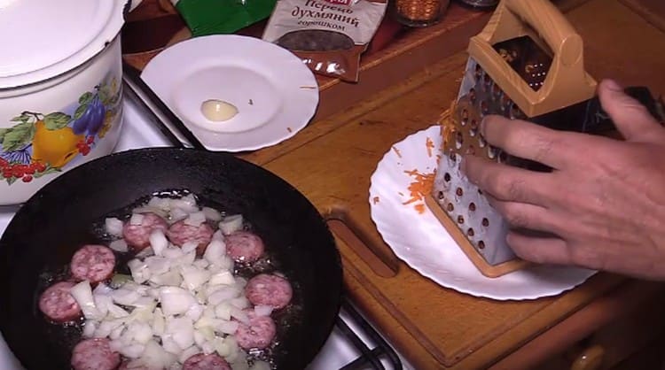 Προσθέστε το κρεμμύδι στο λουκάνικο στο τηγάνι.