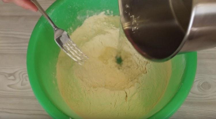 Inserisci acqua bollente nella farina, mescolando l'impasto.