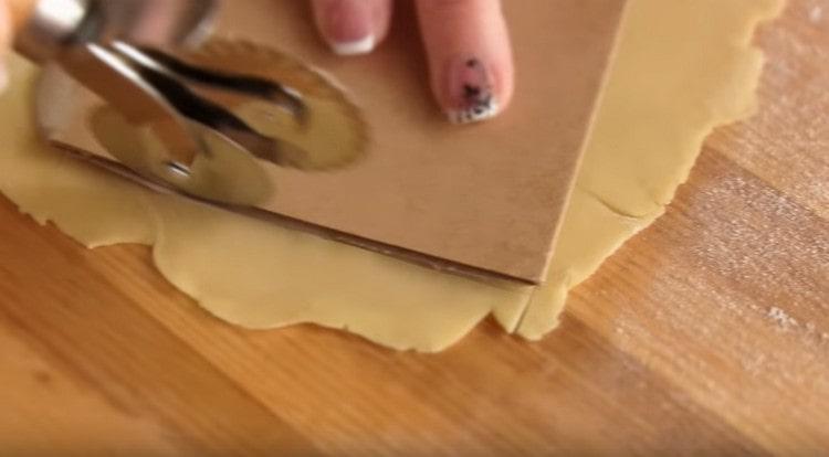 Usando un modello, tagliamo i fogli per le lasagne.