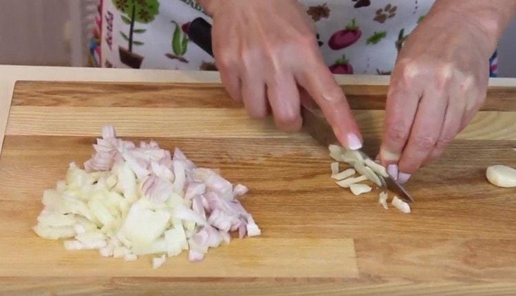 Tritare le cipolle e l'aglio.