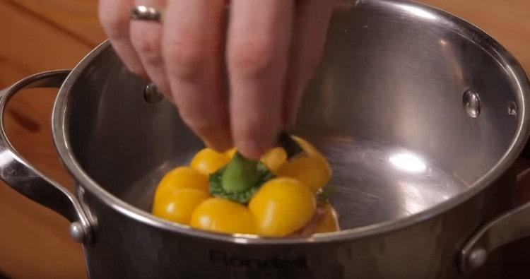 Διανέμουμε τις πιπεριές σε ένα τηγάνι, καλύπτουμε με καπέλα.