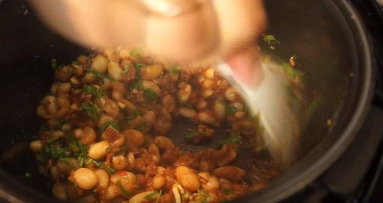 Aggiungi coriandolo con aglio a un piatto quasi pronto.