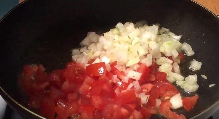 Pirmiausia į keptuvę sudėkite svogūnus ir pomidorus.