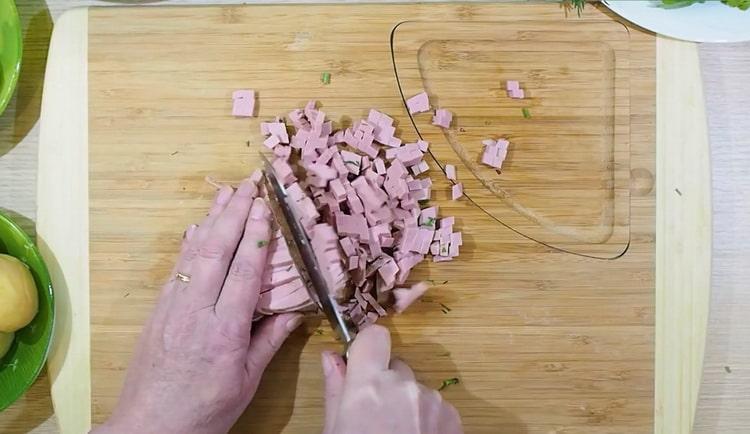 Per cucinare okroshka, tagliare la salsiccia