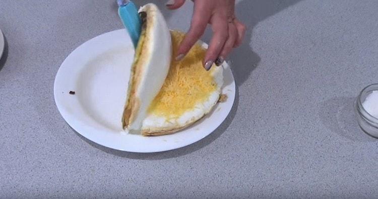 Das Omelett vorsichtig abschneiden und mit der freien Hälfte des Käses bedecken.