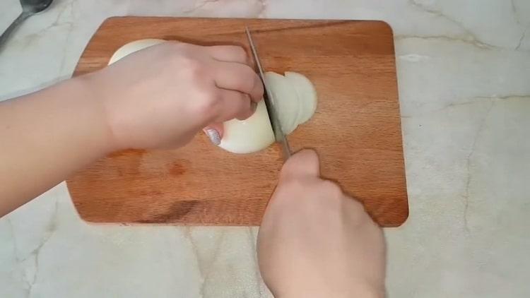 Für die Zubereitung von Kohlpasteten Zwiebeln hacken