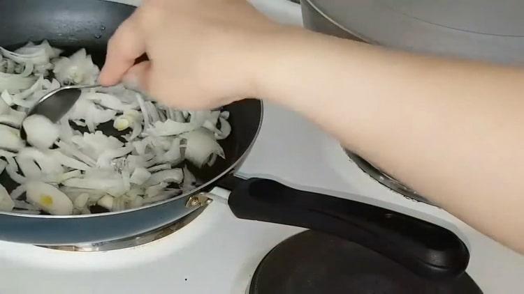 Die Zwiebel anbraten, um die Kohlpasteten zuzubereiten