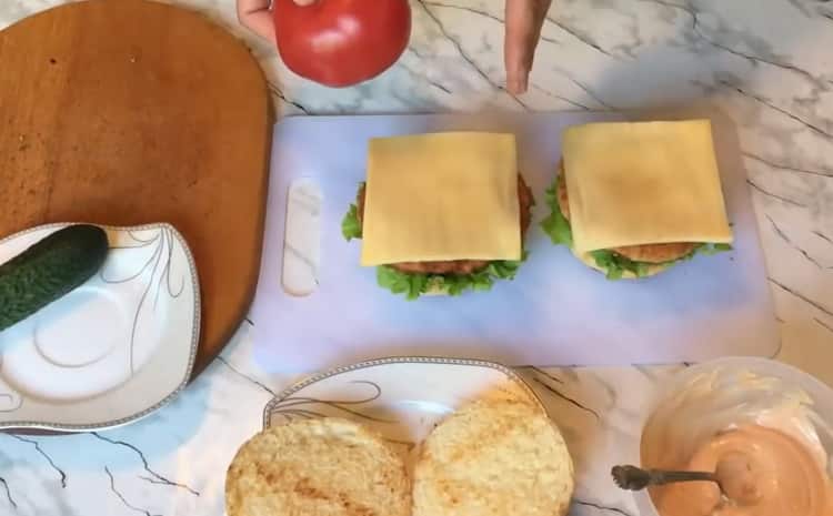 Per preparare un chickenburger, metti il ​​formaggio su un panino
