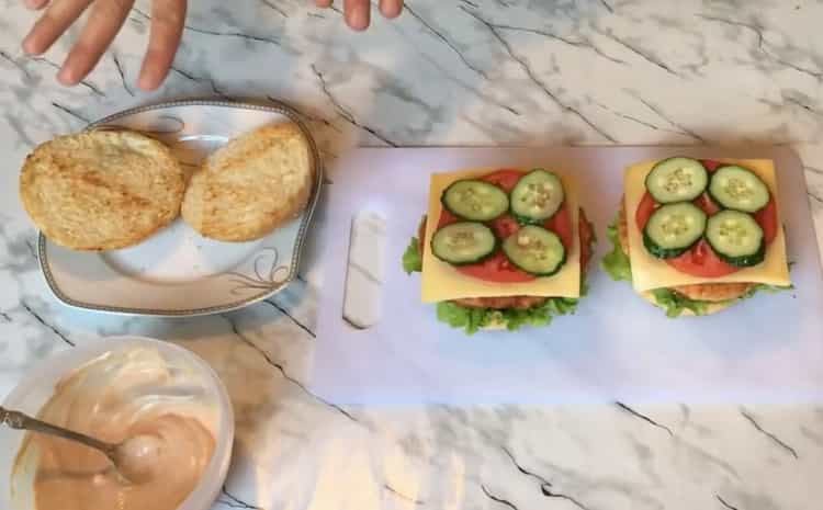 Per preparare un chickenburger, metti le verdure su un panino