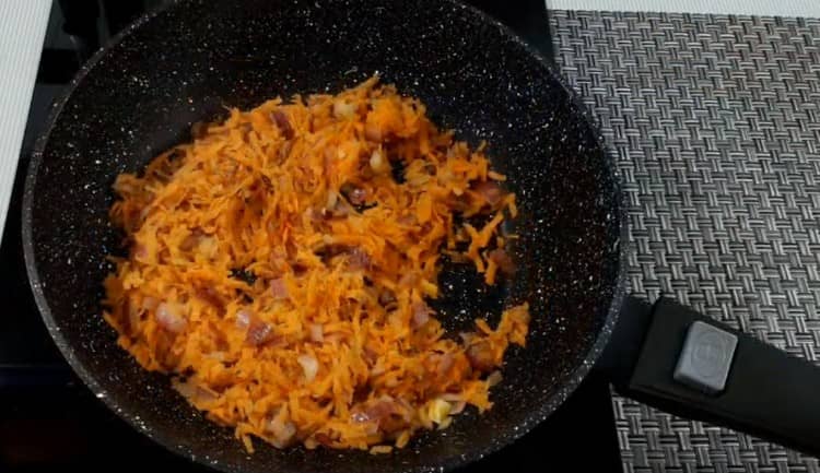 Fügen Sie der Zwiebel Karotten hinzu und lassen Sie das Gemüse einige Minuten köcheln.