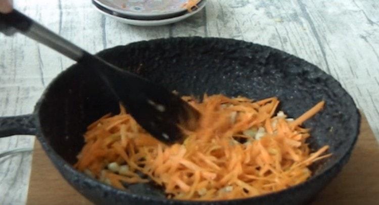 Fügen Sie Karotten der Zwiebel hinzu und lassen Sie sie noch einige Minuten köcheln.