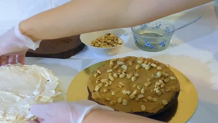 Upang makagawa ng isang cake, iwisik ang cream na may mga mani.