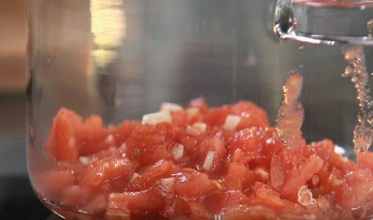 Tomaten fein hacken, mit Knoblauch mischen und in einen Topf geben.