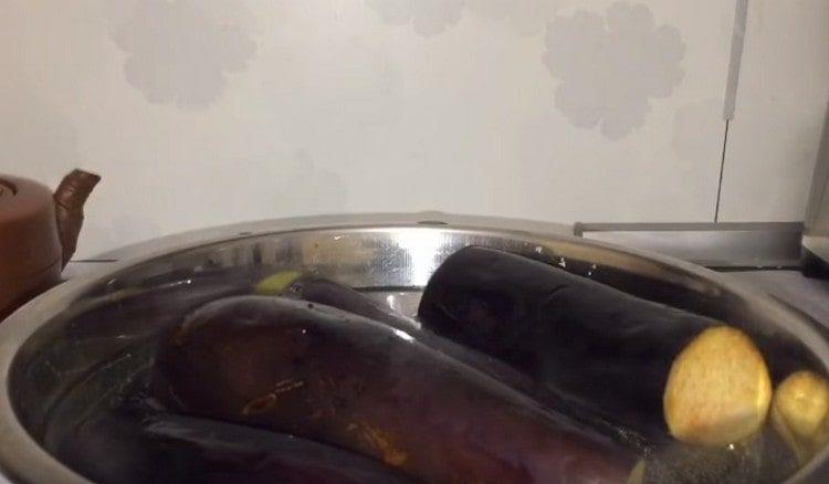 Nachdem Sie die Schwänze der Aubergine geschnitten haben, geben Sie sie in einen Topf mit kochendem Wasser und kochen Sie sie 7 Minuten lang.
