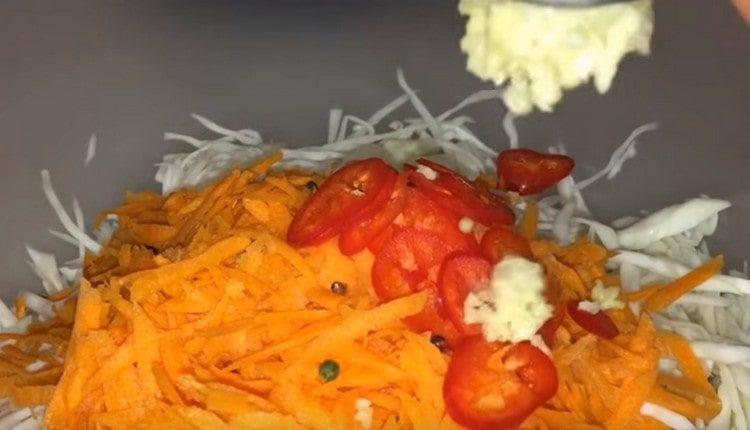 Στο λάχανο με τα καρότα, προσθέστε ψιλοκομμένες πιπεριές και πιπέρι, πιέστε το σκόρδο.