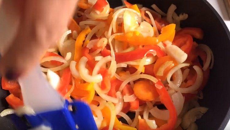 tagliamo anche cipolle, peperoni, aggiungiamo alle carote in padella.