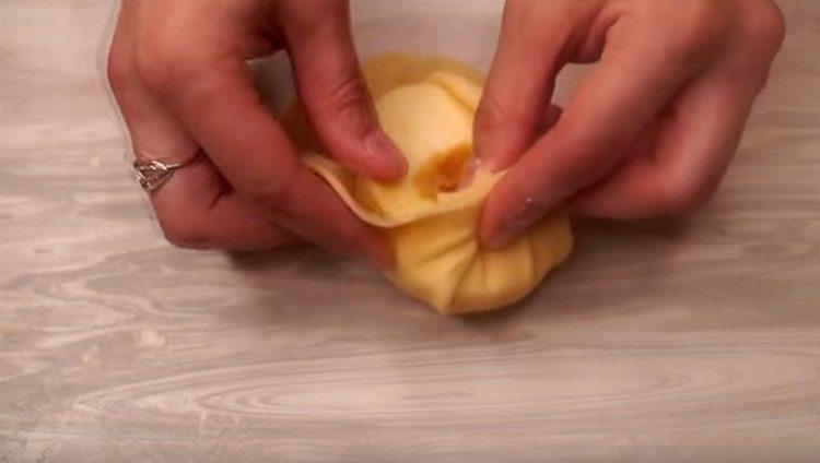 Βάλτε το μισό μήλο στο κέντρο κάθε κέικ και συλλέγετε τη ζύμη γύρω από αυτό με μια τσάντα.