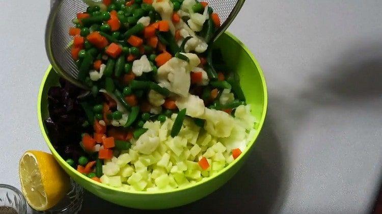 A korábban főtt zöldségkeveréket áthelyezzük a salátára.