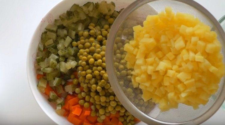 Fügen Sie gekühlte Kartoffeln und Dosenerbsen zum Salat hinzu.