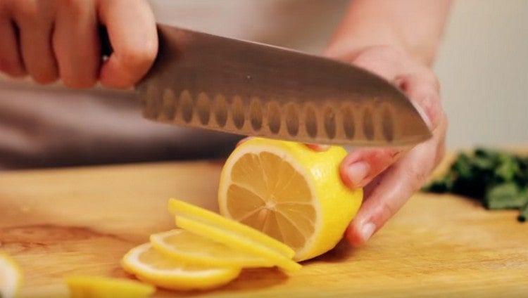 Zitrone in dünne Scheiben schneiden.