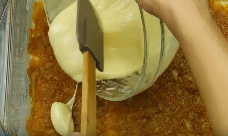 Разпределяме ябълковия пълнеж отгоре върху предварително изпечената основа и изсипваме останалото тесто.