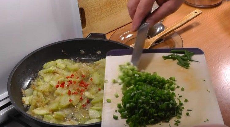 Προσθέστε ψιλοκομμένο καυτό πιπέρι και πράσινο κρεμμύδι στο τηγάνι.