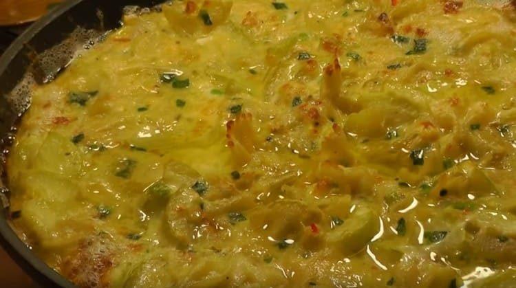 Beveik baigtas cukinijas su kiaušiniais keptuvėje taip pat galima apibarstyti tarkuotu sūriu.
