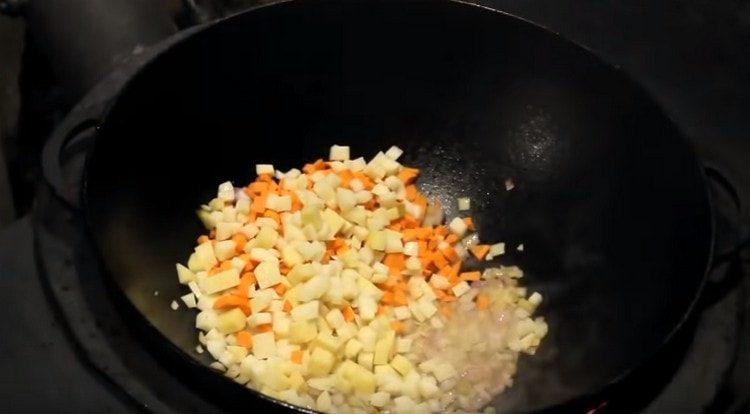 Fügen Sie fein gehackte Karotten und Kartoffeln der Zwiebel hinzu.