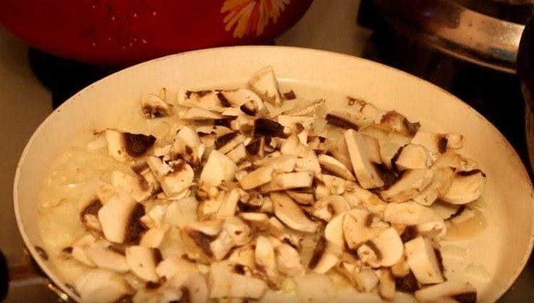 Friggere la cipolla con i funghi in una padella.