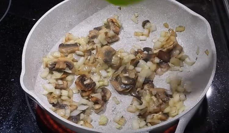Προσθέστε ψιλοκομμένα κρεμμύδια στα μανιτάρια, τηγανίζετε.