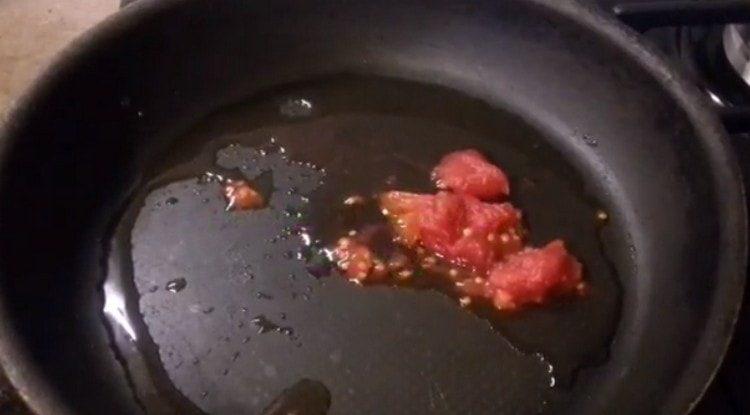 Die Tomate reiben und in einer Pfanne verteilen.