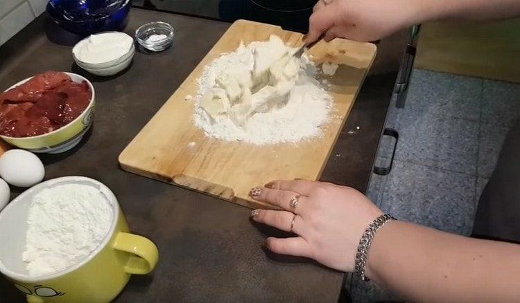 Gießen Sie das Mehl, verteilen Sie die Butter in Stücke in das Mehl.