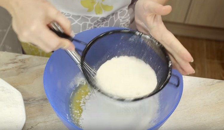 Gießen Sie Mehl in kleinen Portionen und kneten Sie den Teig.