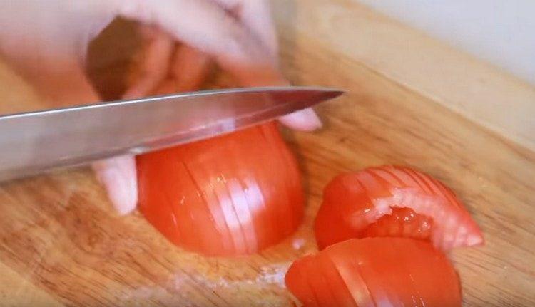 Wir schneiden Tomaten in dünne Scheiben.
