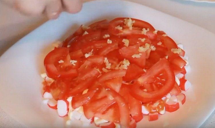 paskirstykite pjaustytą česnaką ant pomidorų, pagaminkite majonezo tinklą.