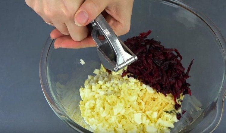 Passare l'aglio attraverso la pressa e aggiungere l'insalata.