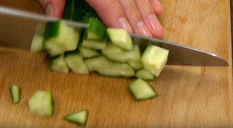 taglia un cetriolo fresco.
