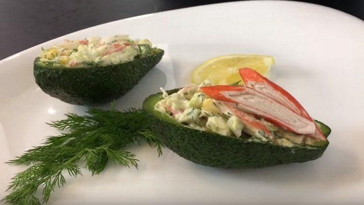 Wir servieren einen Salat mit Avocado- und Krabbenstäbchen in Avocado-Schalenbooten.