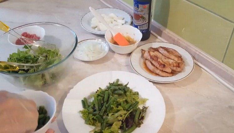 Salat auf einem Teller verteilen, dann Bohnen.