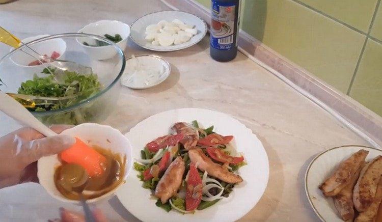 Idagdag ang hiwa na pinatuyong kamatis, ibuhos ang salad sa sarsa.