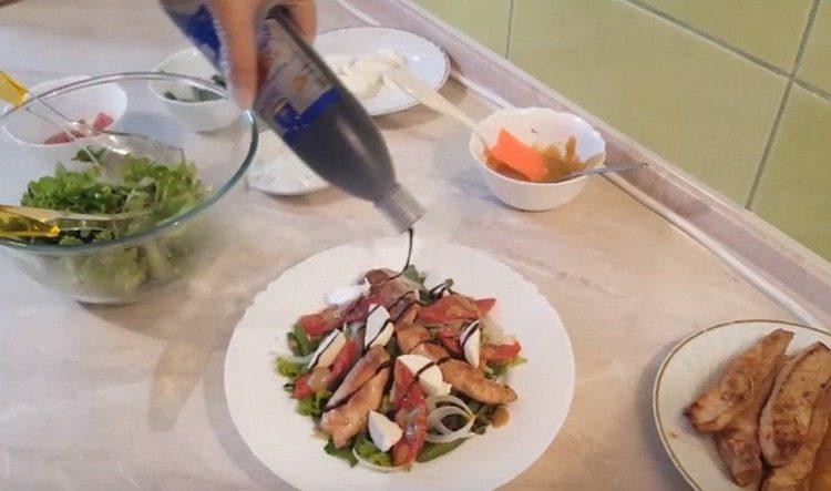 Wir dekorieren den Salat mit sonnengetrockneten Tomaten mit Mozzarellascheiben und gießen Balsamico darauf.