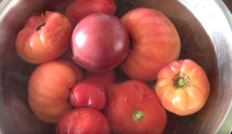 Versare i pomodori con acqua bollente, quindi trasferirli in acqua fredda.