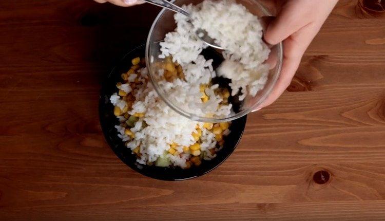 Προσθέστε το βρασμένο ρύζι και το καλαμπόκι στο αγγούρι και τα καβούρια.
