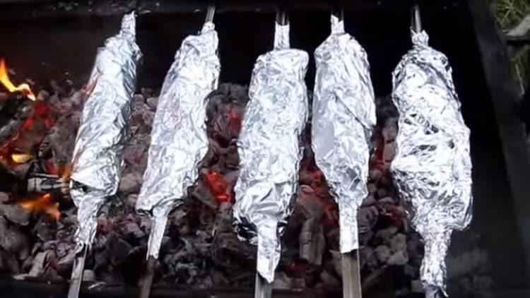 Shish kebab zabalené do fólie se vracejí zpět na gril.