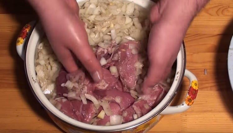 يقلب اللحم مع البصل.